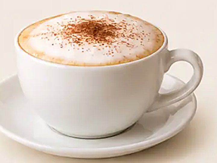 Un cappuccino con cacao espolvoreado en taza blanca